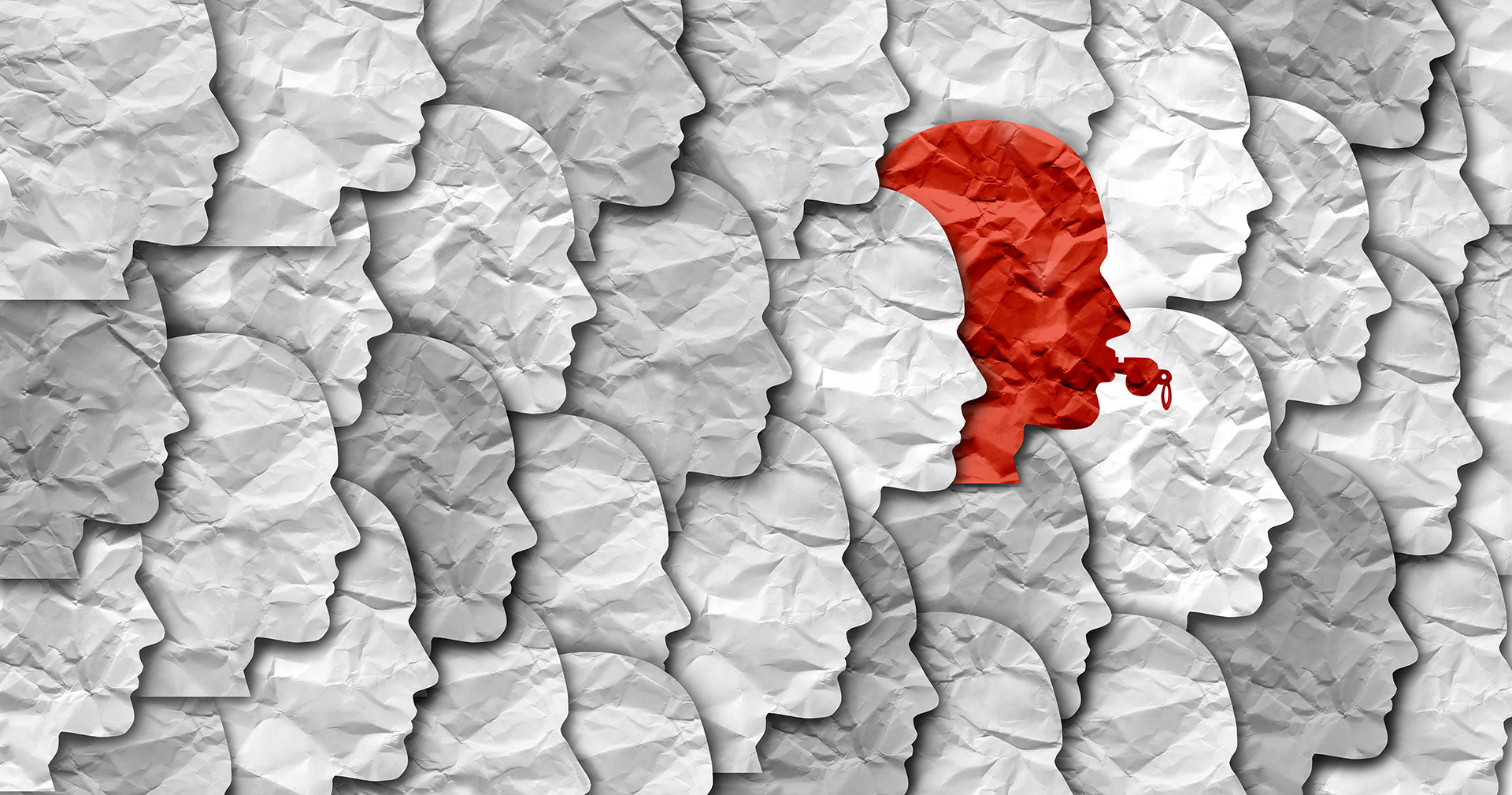 Collage of light grey paper human heads, with one standing out in red